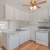 kitchen with wood floors white cabinets a fridge and stovetop