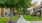 a walkway through a green lawn between buildingsds