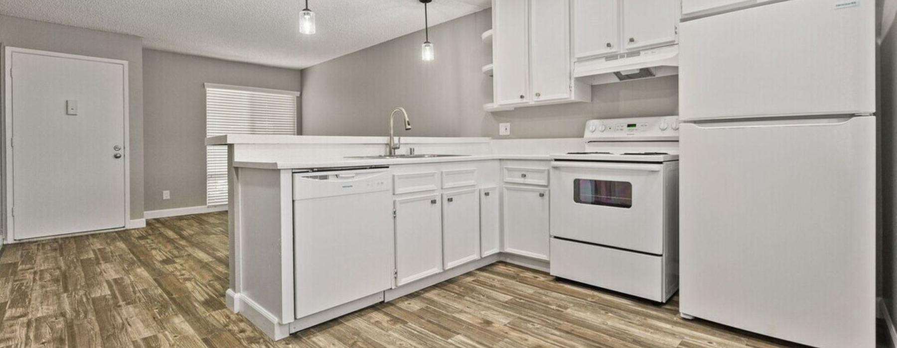 a kitchen with white cabinets and wood-style flooring and a refrigerator